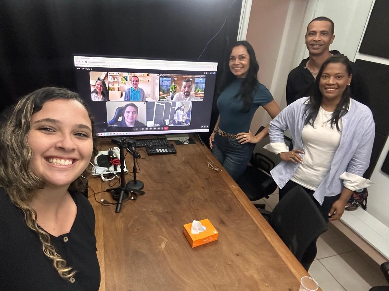 Aula híbrida na Escola de Rádio: alunos presenciais na bancada e colegas na chamada ao vivo na tela