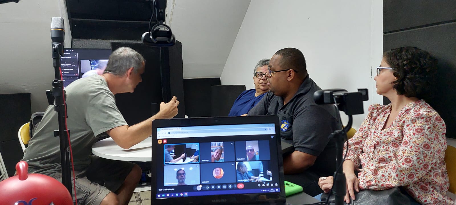 Aula com professor, alunos presenciais e chamada online no laptop