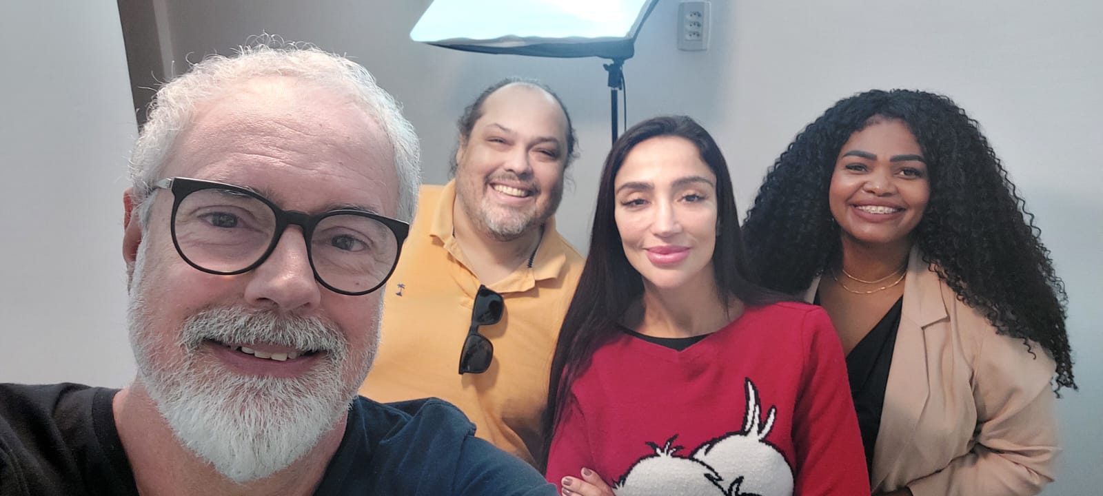 Ruy Jobim em selfie com três alunos no estúdio da Escola de Rádio iluminado por softbox