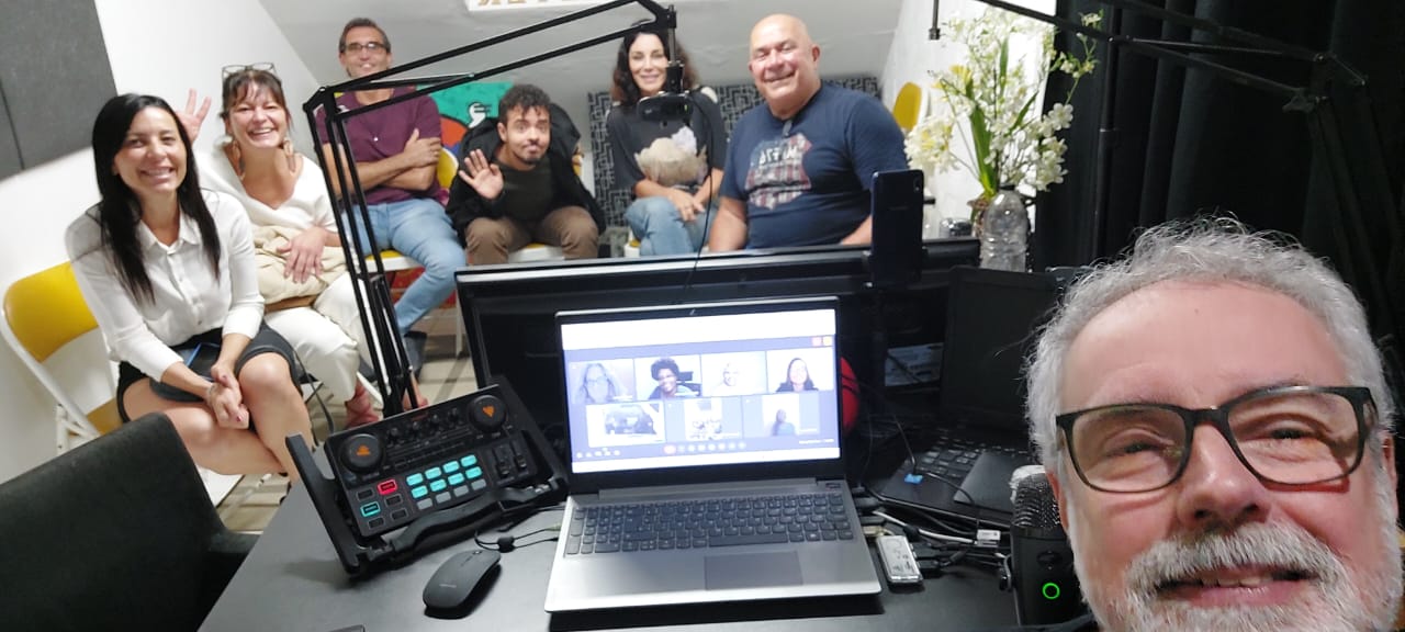 Selfie da turma ao redor da mesa controladora com chamada online no laptop